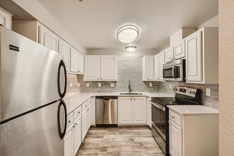 A kitchen with white cabinets and a black fridge.