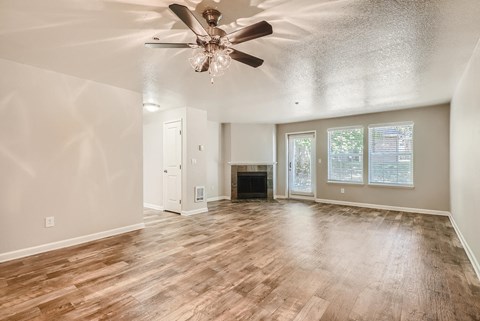 A spacious living room with wood flooring and a ceiling fan.