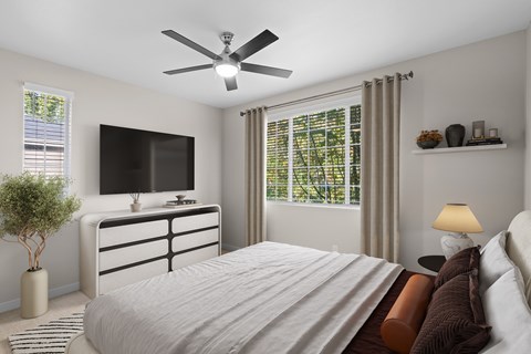 A bedroom with a large bed, a flat screen TV, and a ceiling fan.