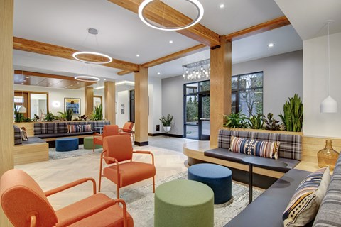 A modern living room with a grey sofa, orange chairs and a wooden bench.