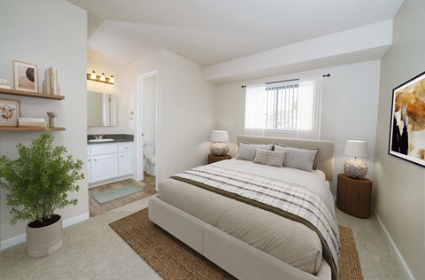A bedroom with a large bed and a potted plant.