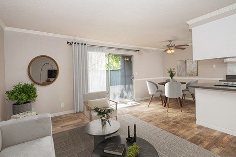 A modern living room with a grey sofa, a coffee table, and a dining table set up.