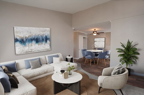 A living room with a white couch, a coffee table, a chair, and a painting on the wall.
