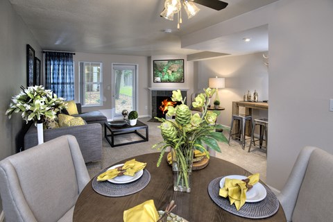 A dining room with a table set for two and a ceiling fan.