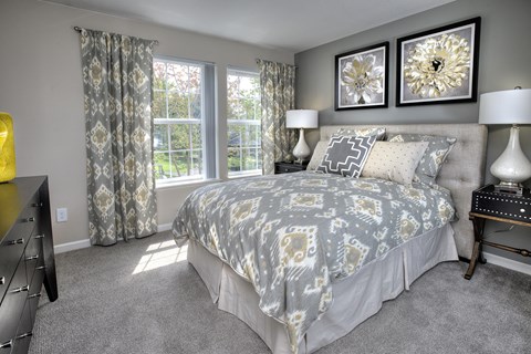 A bedroom with a large bed and two wall lamps.