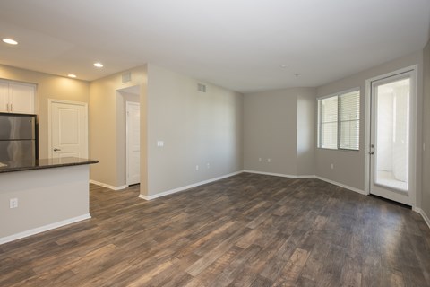 A spacious room with wooden flooring and white walls.