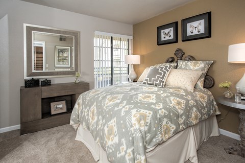 A bedroom with a large bed and a mirror above a dresser.