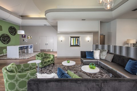 A modern living room with a grey couch and green chairs.