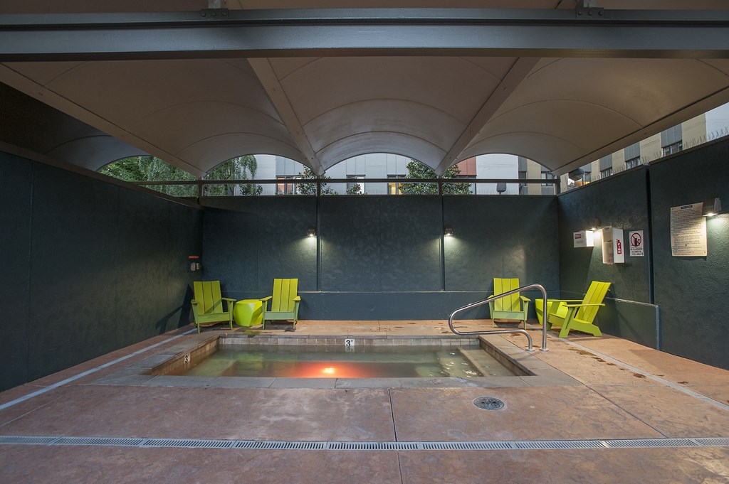 a hot tub and green chairs in a room with a window
