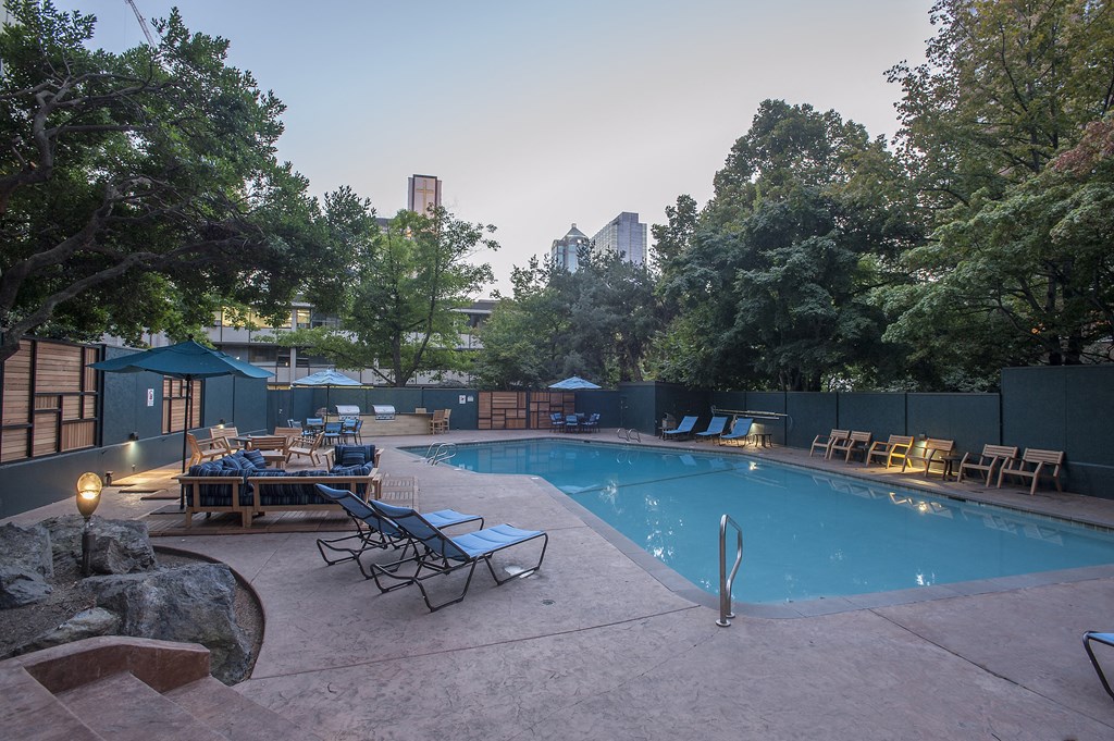 a pool with chairs and tables and a city in the background