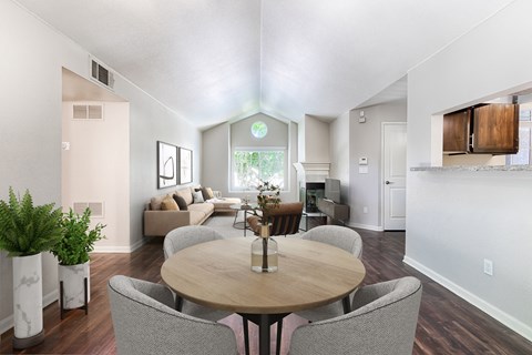 A dining room with a round table surrounded by grey chairs.