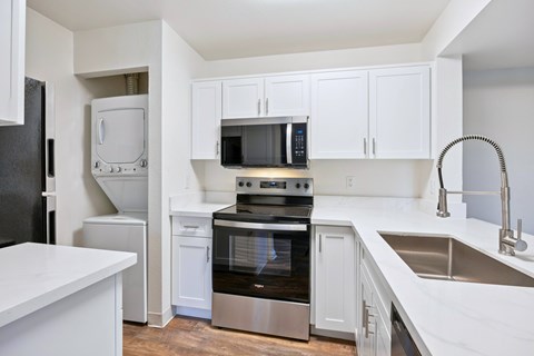 A kitchen with white cabinets and a black fridge.