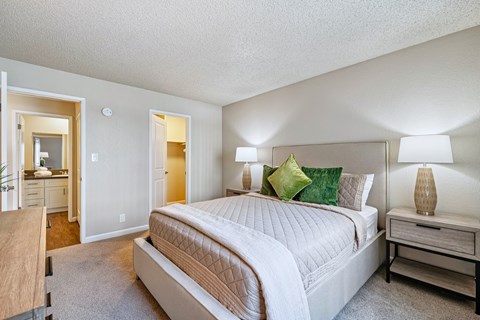A bedroom with a large bed and a nightstand with a lamp.