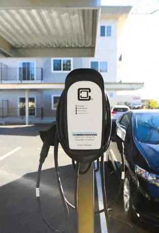 A black electric car is plugged into a charging station.