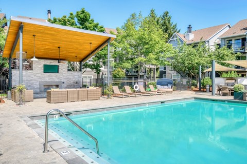A swimming pool with a glass enclosure and a yellow roofed pavilion.