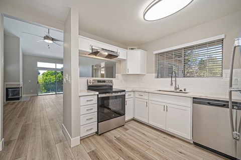 A modern kitchen with white cabinets and wooden floors.