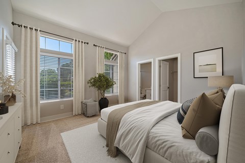A bedroom with a large bed and a window with blinds.