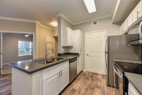 A kitchen with white cabinets and a black countertop.