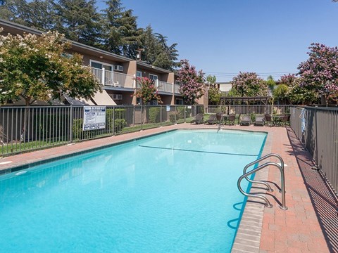 A swimming pool surrounded by a fence and trees.