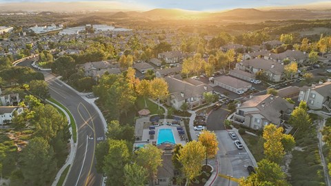 A sunset view of a residential area with houses and a pool.