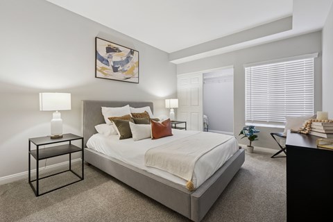 A bedroom with a large bed, a nightstand with a lit candle, and a painting on the wall.