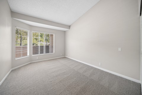 A room with a carpeted floor and a window with blinds.