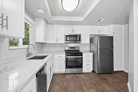 A modern kitchen with white cabinets and stainless steel appliances.
