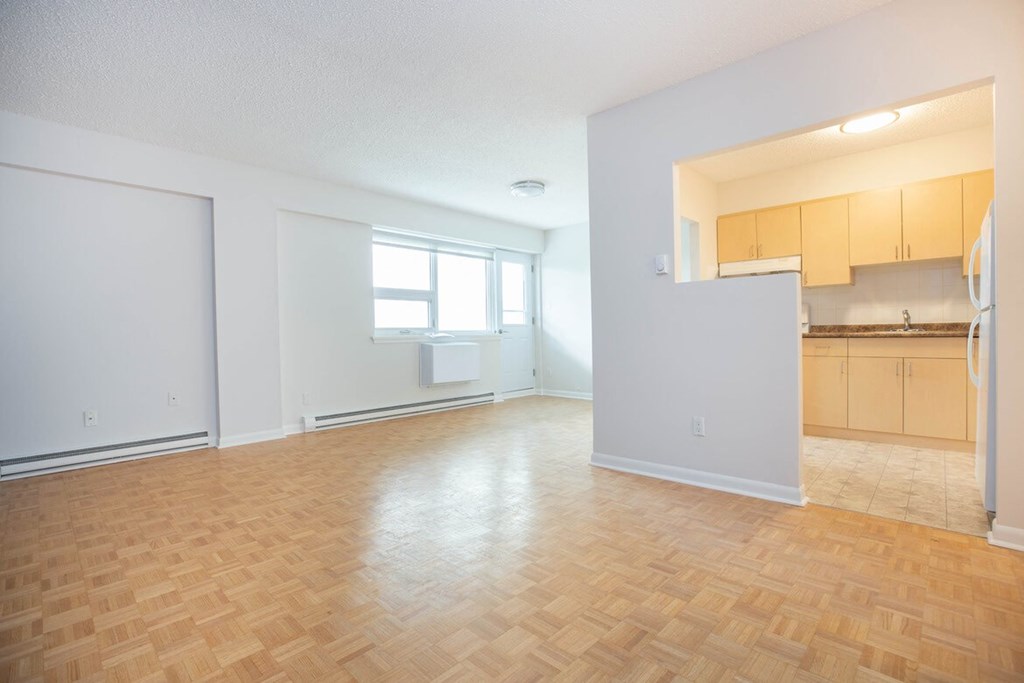 an empty living room and kitchen with wood flooring