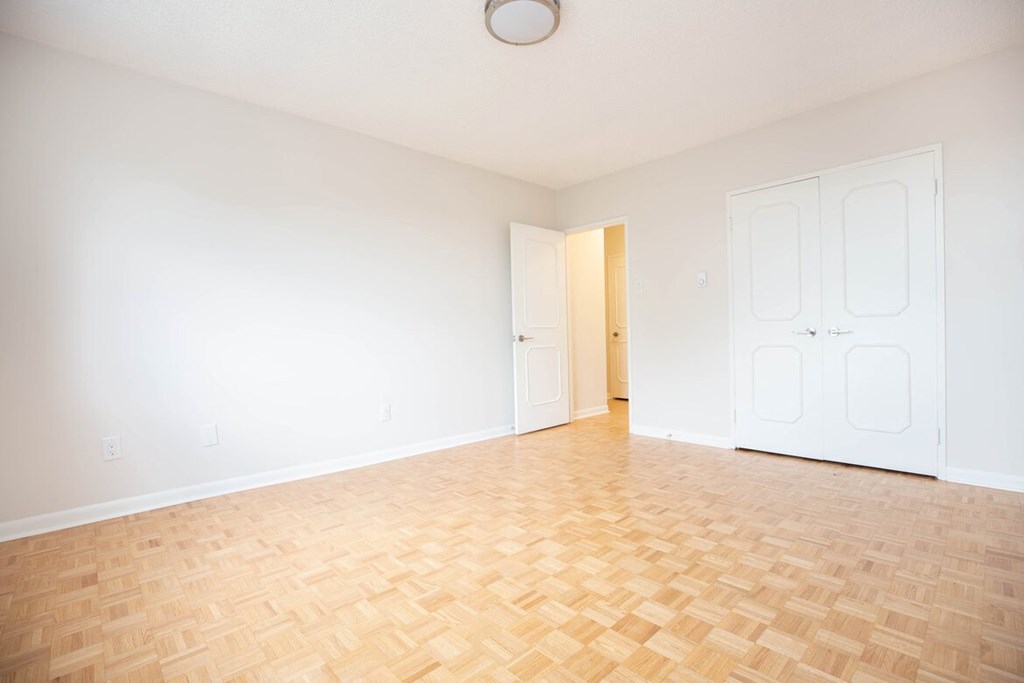 an empty living room with a wooden floor and white doors