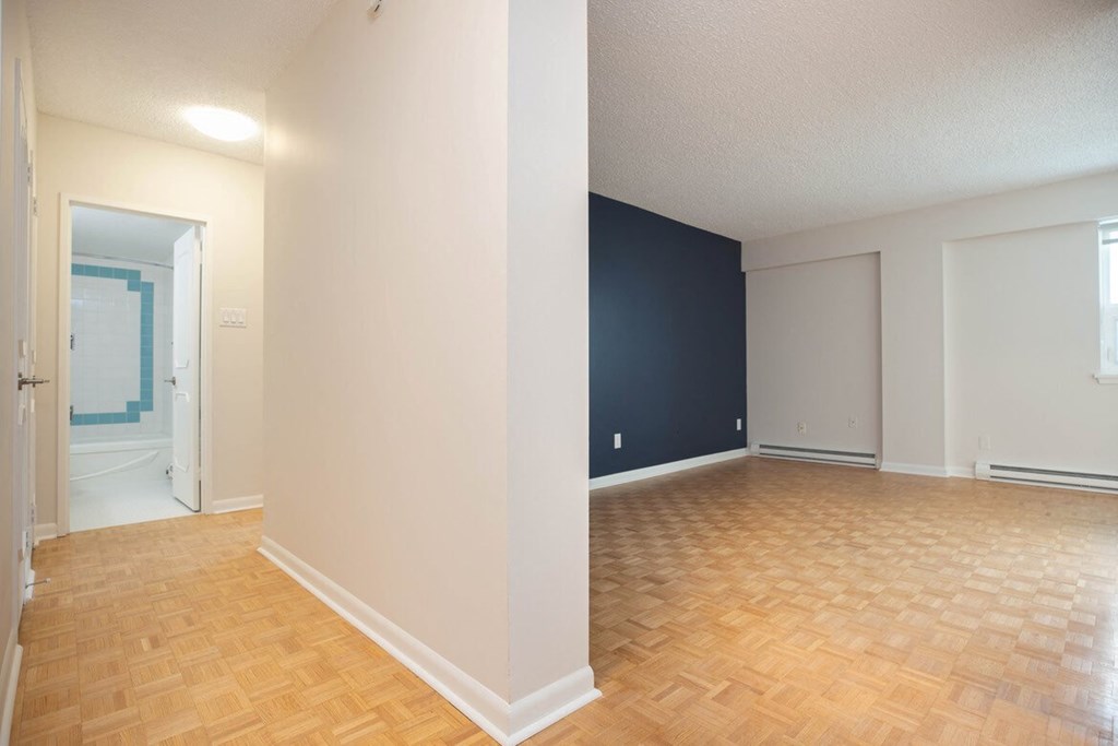 an empty living room with wood flooring and a blue accent wall