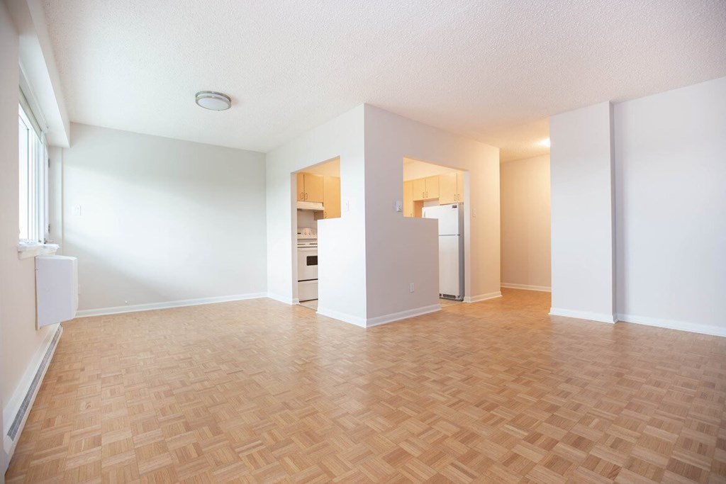 an empty living room and kitchen with a wood floor
