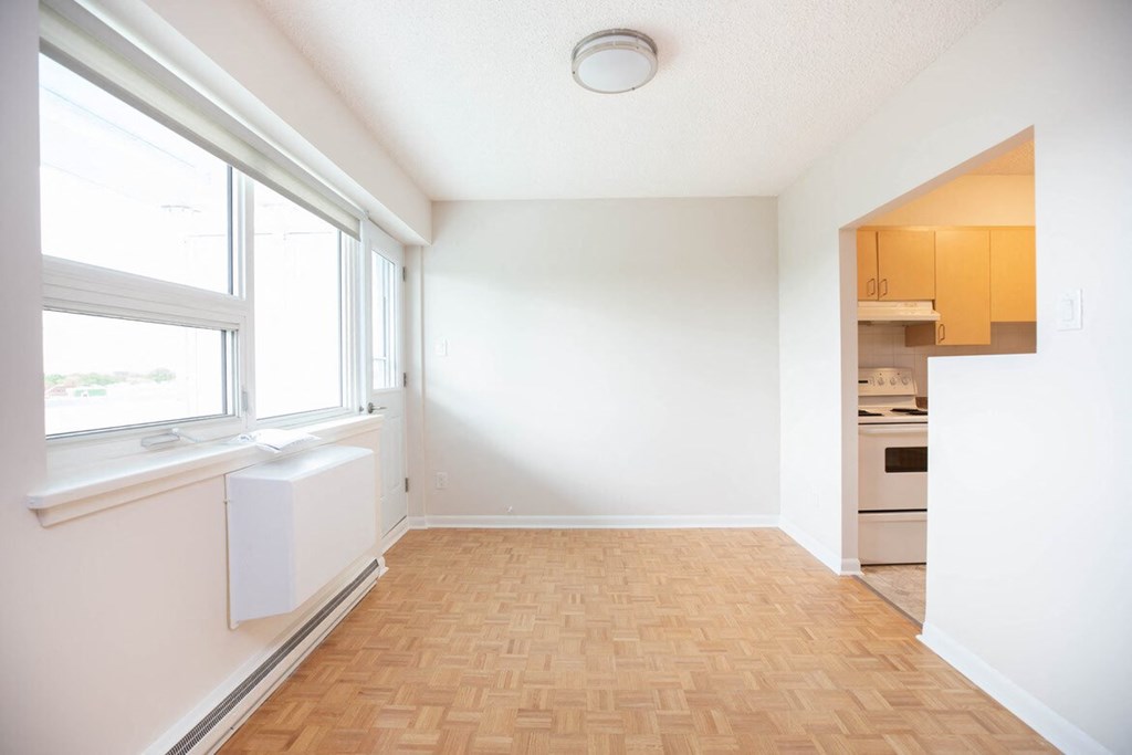 a empty living room with a window and a kitchen