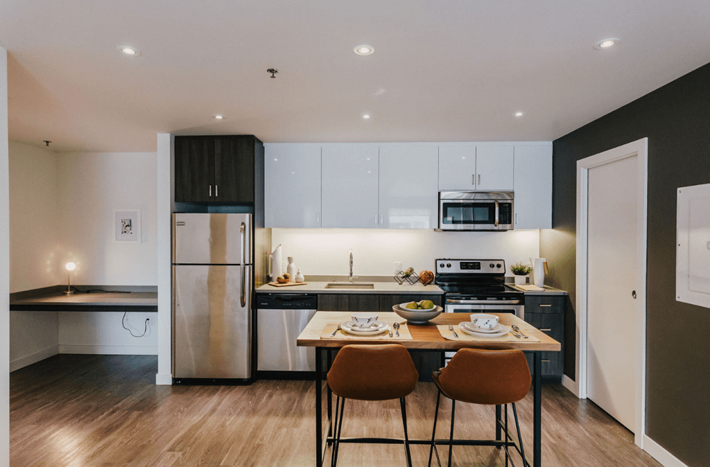 a kitchen with white cabinets and stainless steel appliances and a wooden table