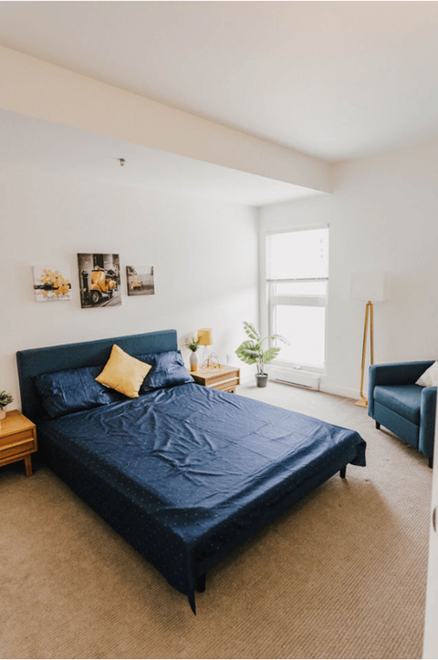 a bedroom with a bed and two blue chairs