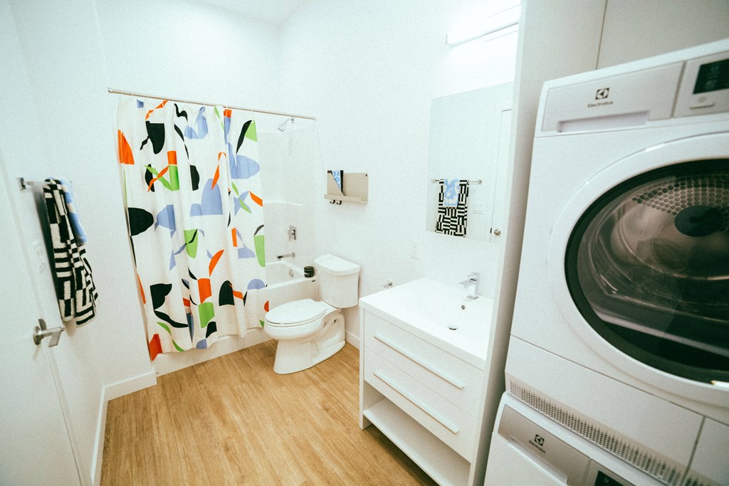 a bathroom with a washing machine and a shower and a toilet