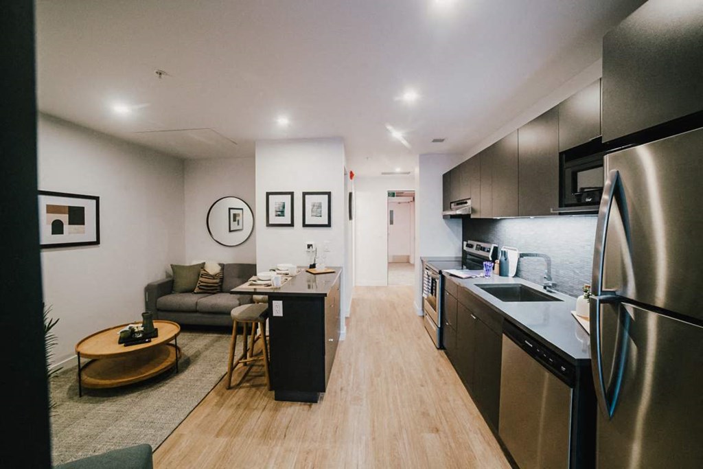 a kitchen and living room with a refrigerator and a sink