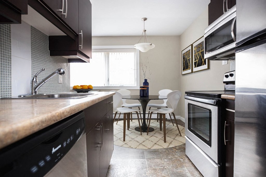 a kitchen with stainless steel appliances and a table and chairs