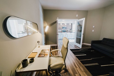 a small living room with a desk and a mirror