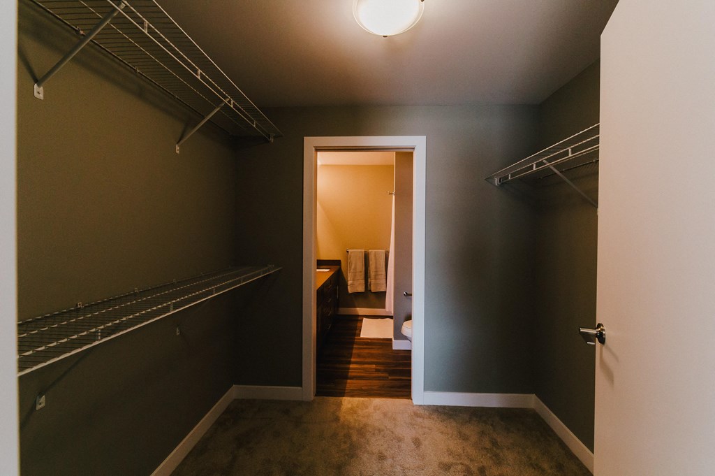 a walk in closet with a mirrored closet door and a door to a bathroom