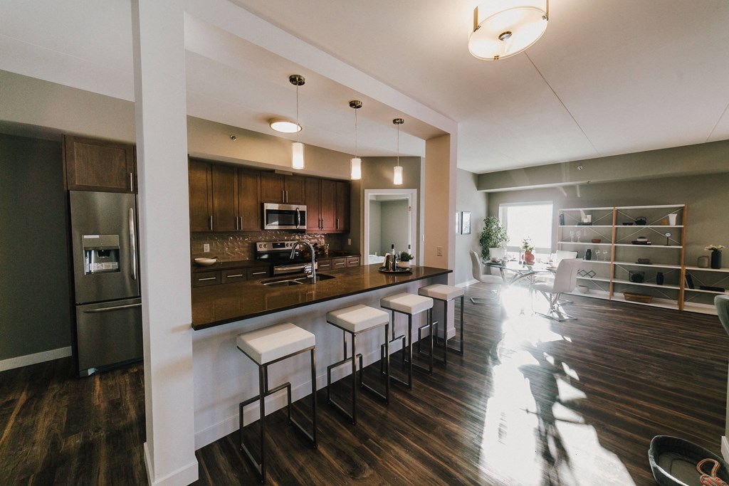 a kitchen and living room with a bar and stools