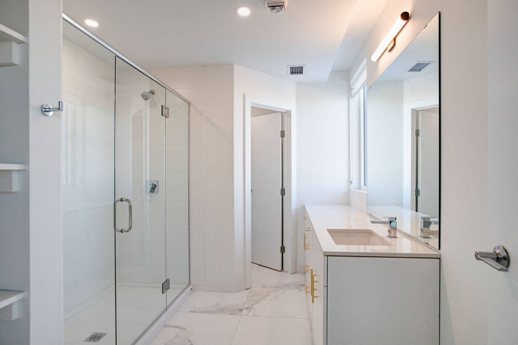 a white bathroom with a shower and a sink
