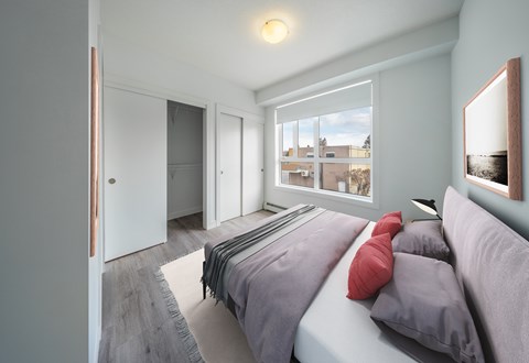 A bedroom with a bed, pillows, and a window overlooking a cityscape.