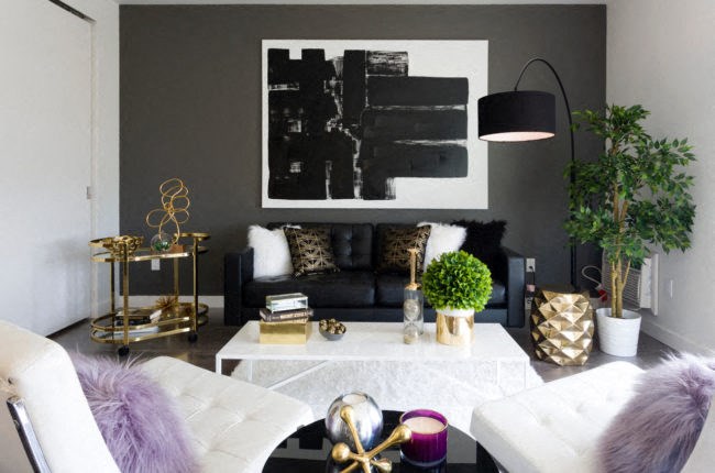 a living room with black and white furniture and a painting on the wall