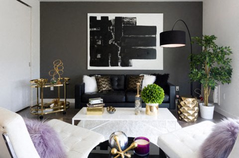 a living room with black and white furniture and a painting on the wall