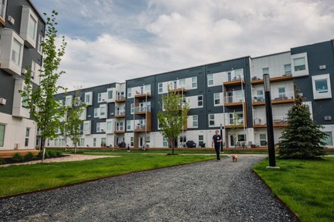 a man walking his dog in front of an apartment building
