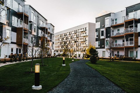 a walkway between modern apartment buildings in a park