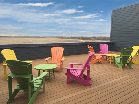 a deck with colored chairs and tables on a roof