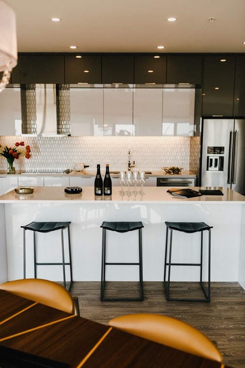 a white kitchen with bar stools and counter tops