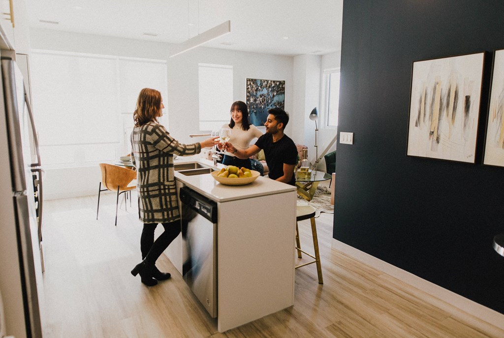 Two women and a man are standing in a kitchen.