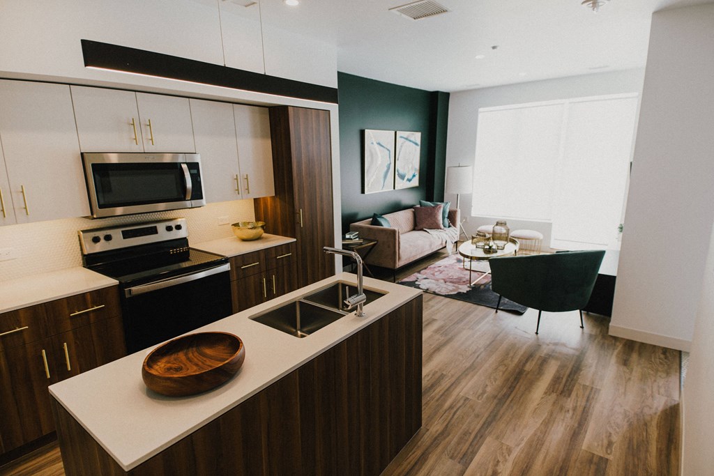 A modern kitchen with dark wood floors and white countertops.